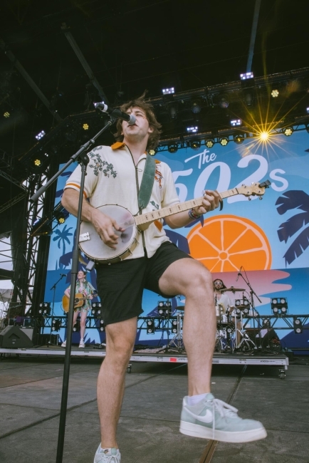 A young man plays the banjo on stage