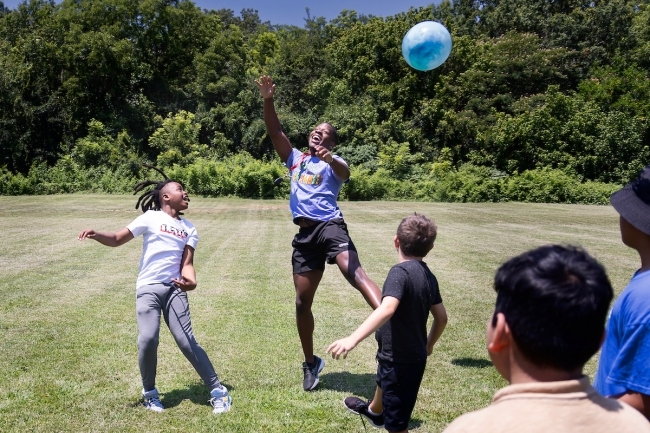 Students playing with ball together on grass field