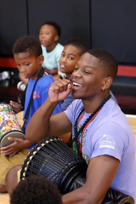A student smiles while holding a drum