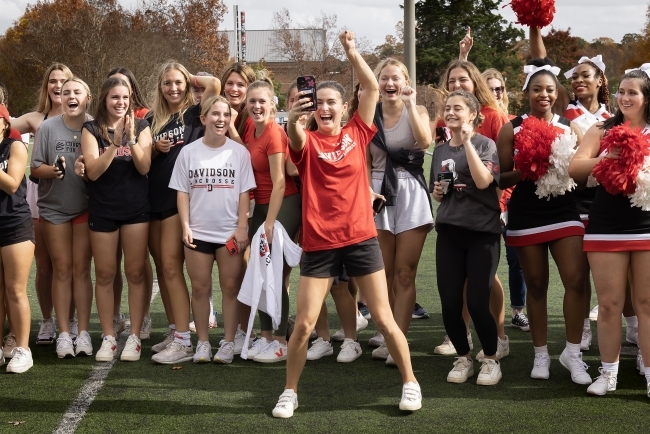 Athletes in Davidson uniforms cheering and taking a selfie
