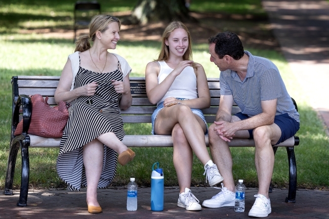 Family sits on bench smiling and talking