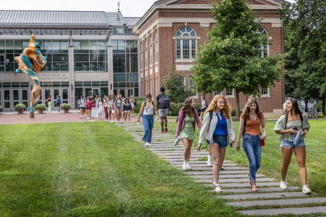 Students walk and laugh in front of Wall Academic Building