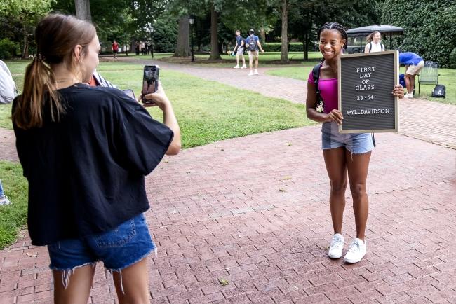 student holds sign for First Day of Classes