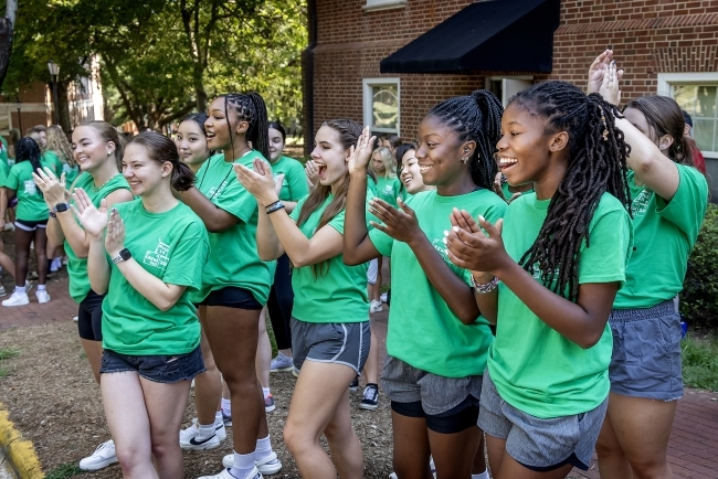 A group of students cheer as cars pull up for move-in