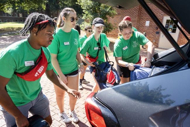 A group of students unpack a car trunk