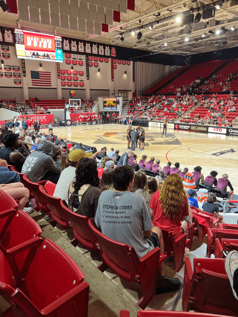 a college basketball court crowded with fans in red