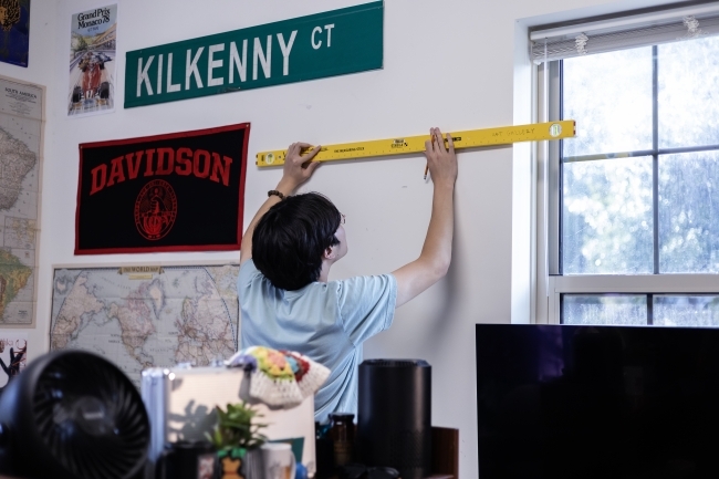 Student Hanging Artmate Art on Dorm Wall