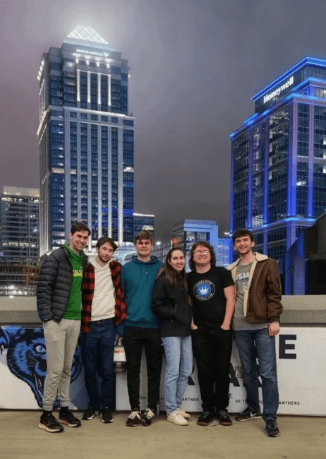 a group of students in front of Charlotte skyline at night