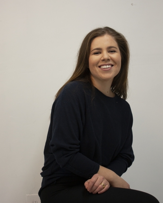 a young woman with brown hair wears black and smiles