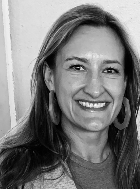 a black and white photo of a woman smiling with long hair and big earrings