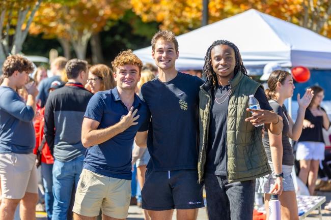 three students smiling at a tailgate