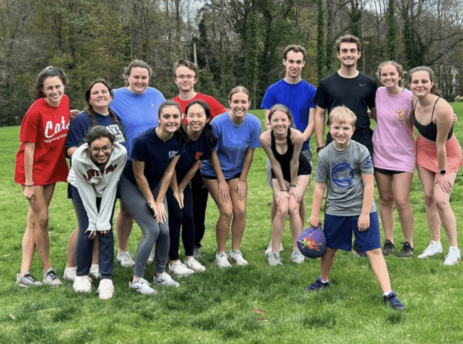 a group of students smiling and standing together on a grassy field outdoors