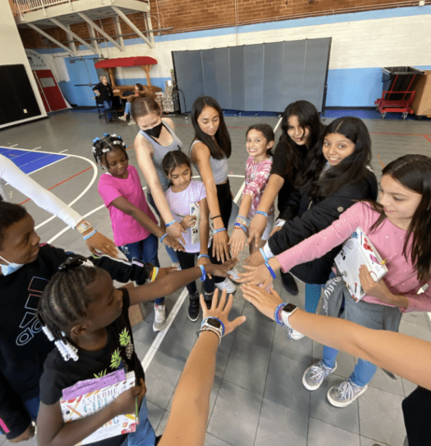 a group of young people huddled together with arms in a circle