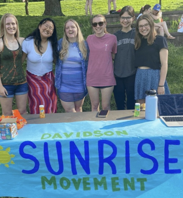 a group of students standing behind a table with a sign that reads "Davidson Sunrise Movement"