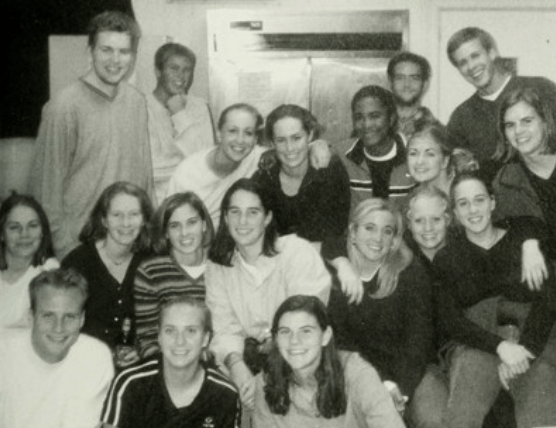 a group of students smiling in a dorm room in a black and white photo
