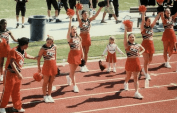 a group of cheerleaders in red and white "Davidson" uniforms cheer on a track