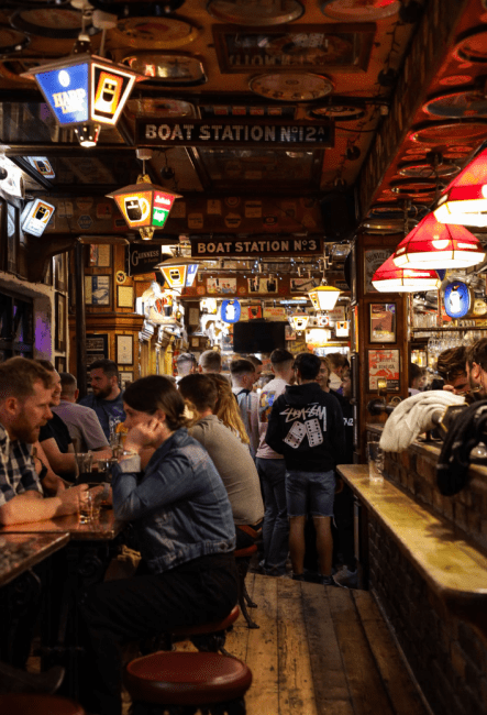 a dark and cozy pub filled with wooden floors and benches