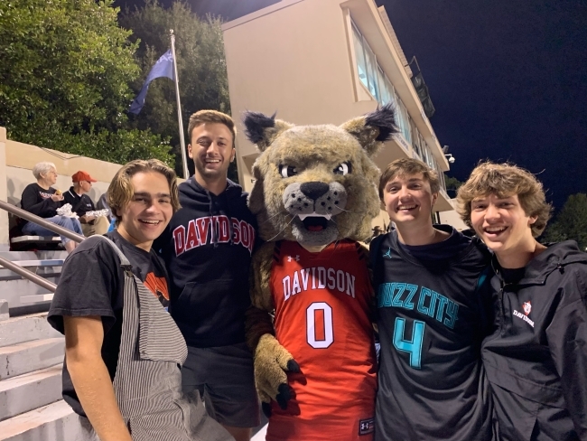 a group of students pose with Wildcat mascot in bleachers