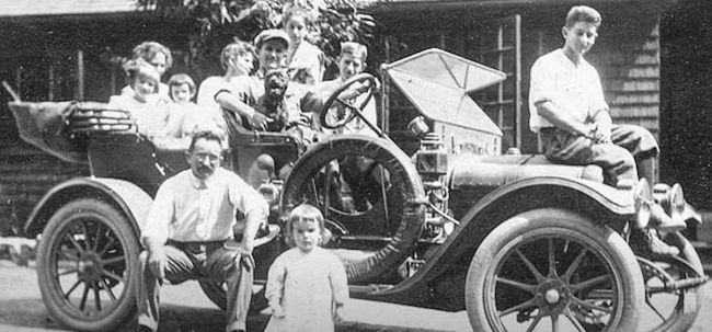 A black and white photograph of a family sitting in an old car