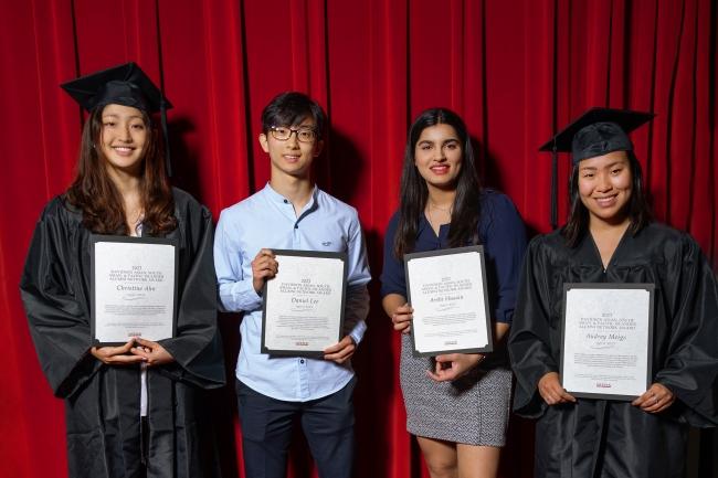 a group of four students holding awards and smiling