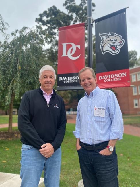 two white men standing outside in front of "Davidson College" banners