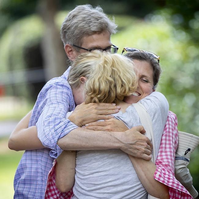 two parents hug their daughter 
