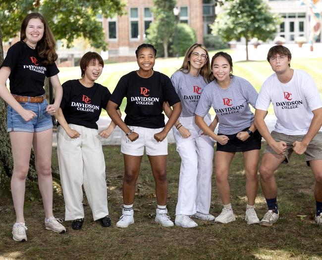 a group of students smiling and showing off tee shirts