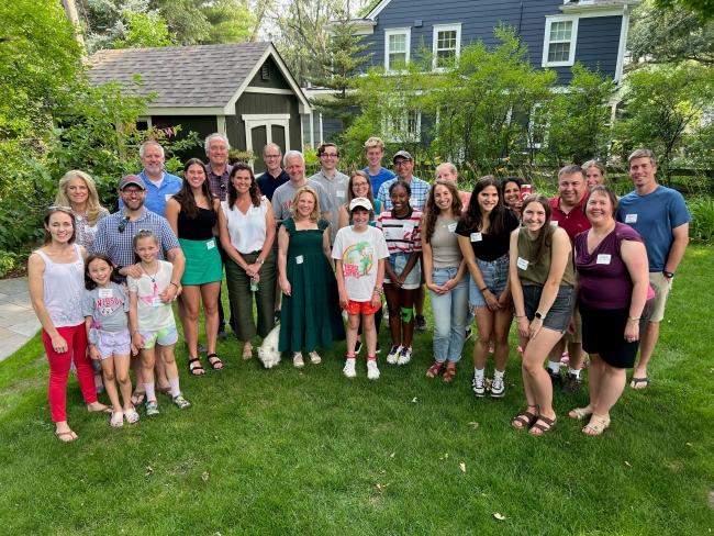 a group of students and their families in a green backyard