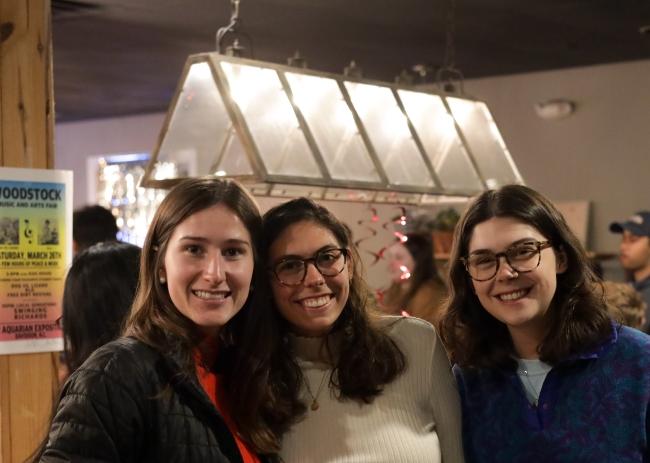 a group of three young women smile in a coffee shop