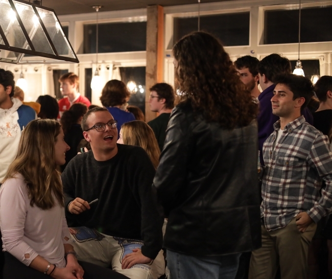 a group of students sit around a table and smile while talking