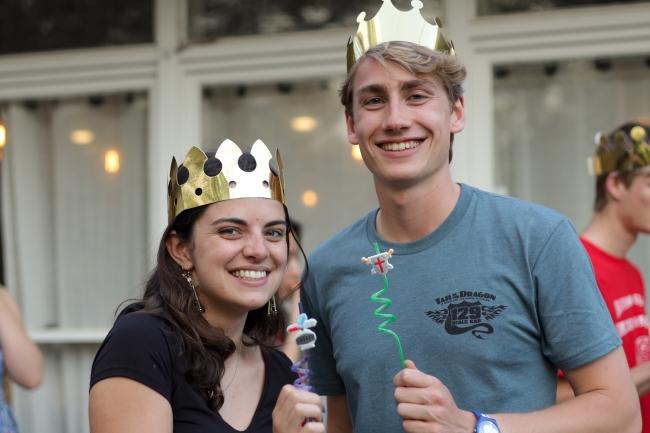 a young man and woman wear gold crowns and smile while holding little wands