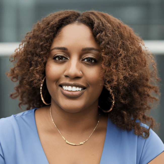 a young Black woman with brown hair wears hoop earrings and a light blue top while smiling