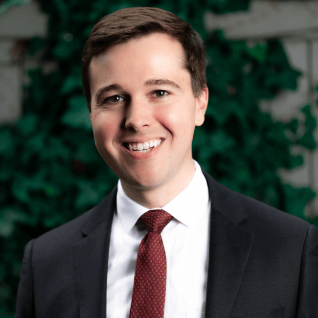 a young white man wearing a suit and tie while smiling