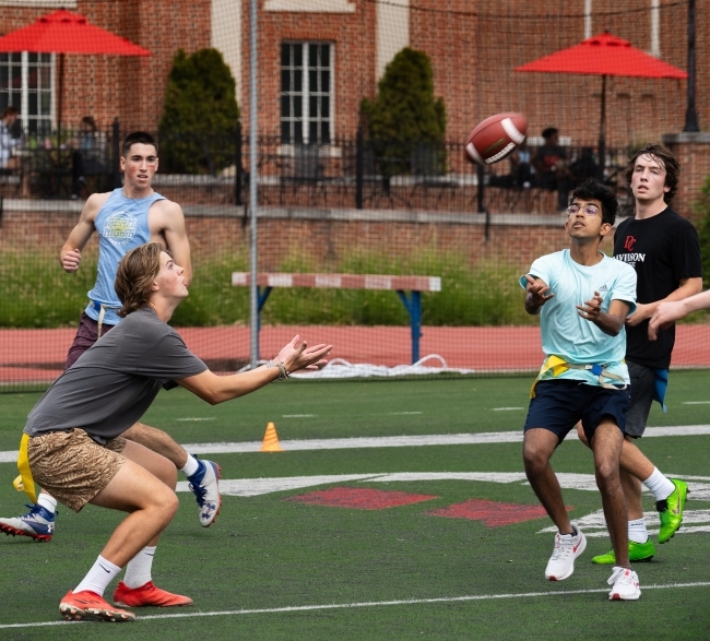 a group of students running with a football on a field