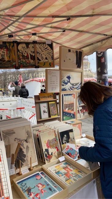 a young person stands over a table of art on a street