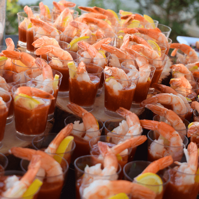 a stack of cups with shrimp in cocktail sauce