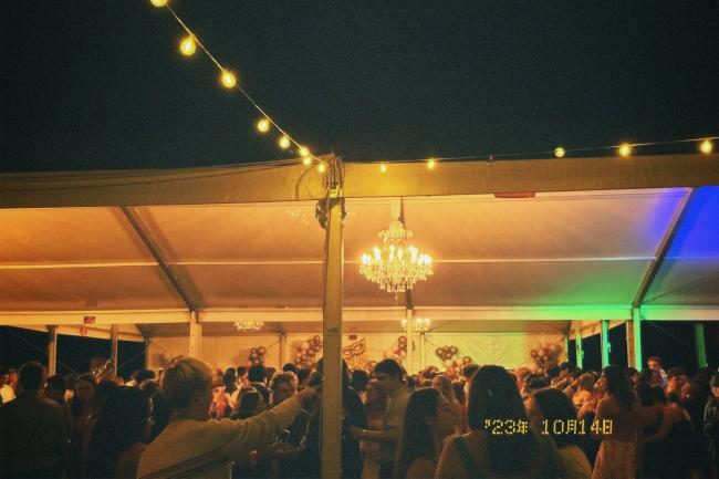 a tent covered in string lights at night and young people dancing underneath it