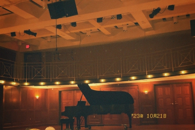 a black piano sits on a stage surrounded by seating and lights