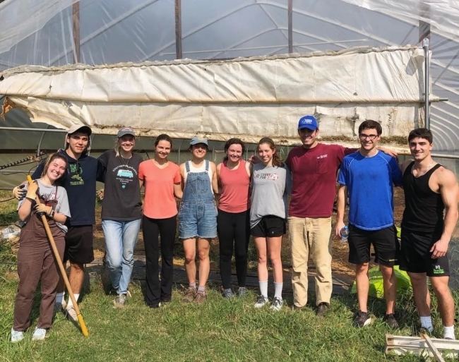 a group of young men and women stand under a greenhouse