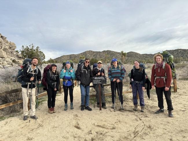a group of young men and women wearing hiking packs