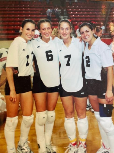a group of four young women in volleyball uniforms smiling