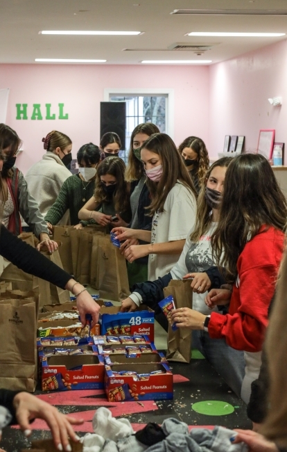 a group of young women package food in brown bags