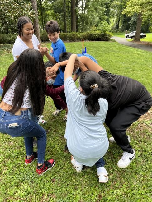 a group of students playing a human knot game outside