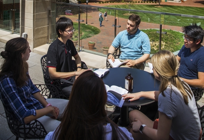 a group of students sit around a table discussing a text