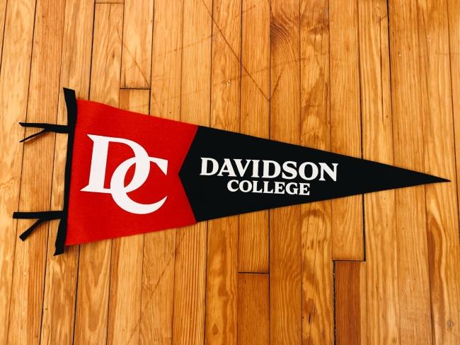 a black and red pennant on a wooden floor that reads "Davidson College"