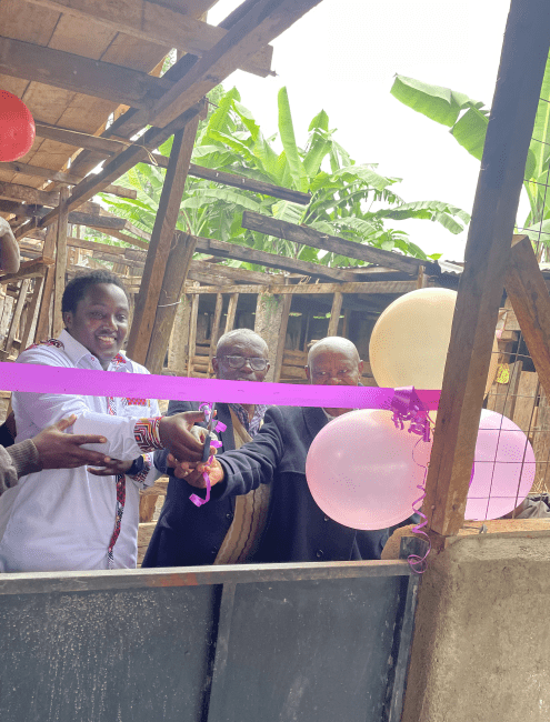 a young Black man holds up scissors as part of a ribbon cutting with two older people