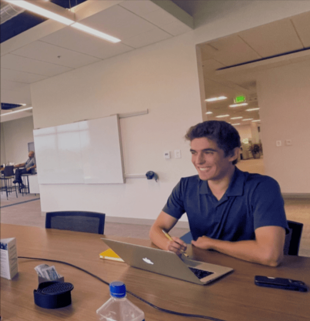 a young white man talks to someone on a laptop