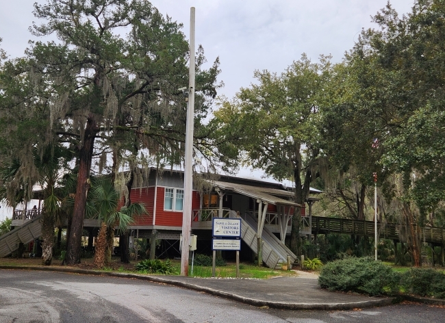 a red wooden building on stilts surrounded by trees