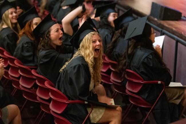 a young white woman laughs while wearing regalia