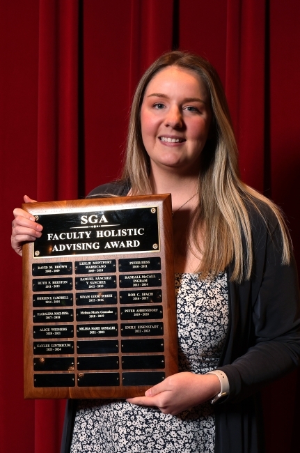 a young white woman holds an award